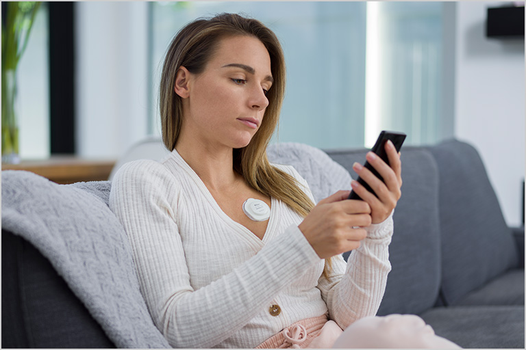 Person on couch with Radius T heart monitor looking at smartphone.