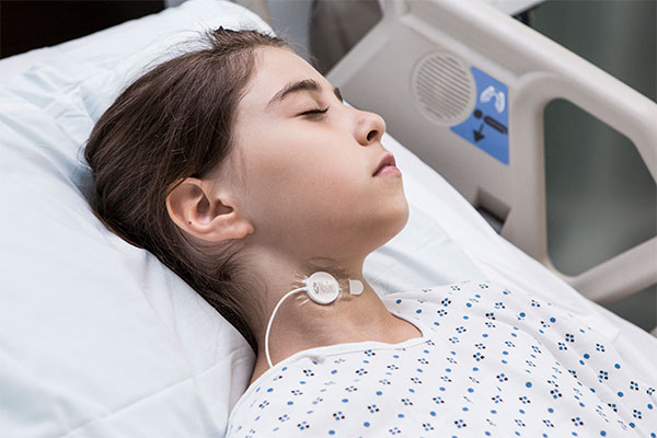 Masimo - Child wearing Acoustic Respiration Rate RRa sensor on neck while in hospital bed